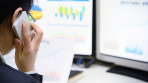 A woman speaks on the phone while analysing data.